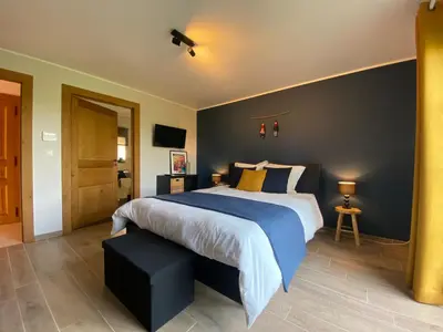a bedroom with a large bed with a blue wall at En Vert & En Pause in Thimister