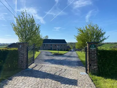 a gate to a brick building with a house at En Vert & En Pause in Thimister
