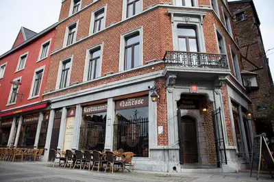 a brick building with tables and chairs on a street at Les Suites de Nanesse in Liège