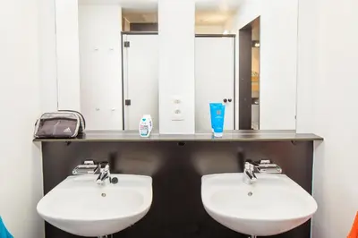 two white sinks in a bathroom with mirrors at Hostel De Veurs in Sint-Martens-Voeren