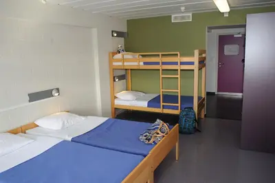 a dorm room with two bunk beds and a ladder at Hostel De Veurs in Sint-Martens-Voeren