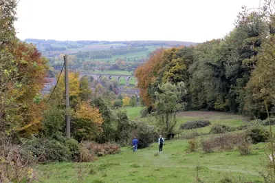 two people walking down a hill in a field at Hostel De Veurs in Sint-Martens-Voeren