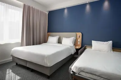 a hotel room with two beds and a blue wall at Holiday Inn Express Hasselt by IHG in Hasselt