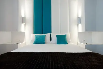 a bedroom with a large white bed with blue pillows at Hotel Ecu in Genk