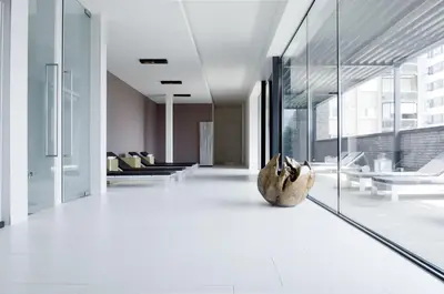 a living room with white floors and glass walls at Hotel Ecu in Genk