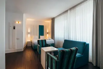 a hotel room with a bed and a couch and chairs at Hotel Ecu in Genk