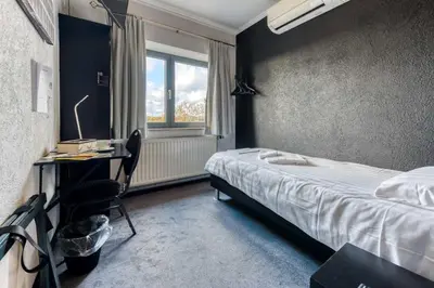 a bedroom with a bed and a desk and a window at Hôtel de la Gare in Visé