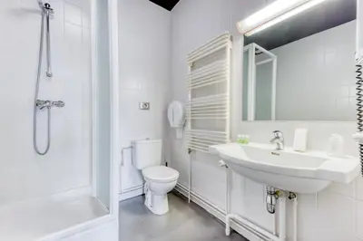 a white bathroom with a sink and a toilet at Hôtel de la Gare in Visé