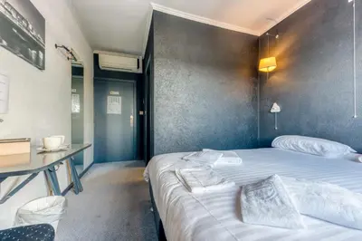 a bedroom with a large bed and a desk at Hôtel de la Gare in Visé