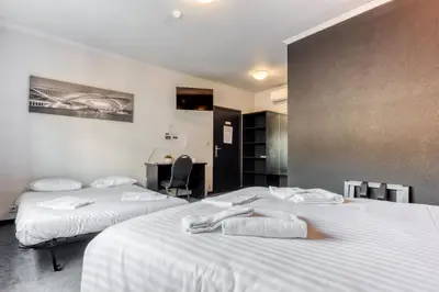 a room with two beds and a desk in it at Hôtel de la Gare in Visé