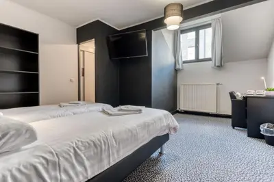 a bedroom with a large bed and a television at Hôtel de la Gare in Visé
