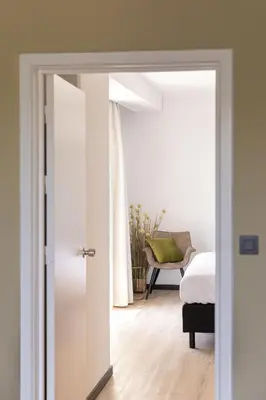 an open door to a bedroom with a bed and a chair at M Hotel in Genk