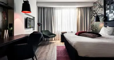 a bedroom with a bed and a desk and a chair at M Hotel in Genk