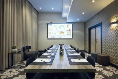 a conference room with a long table and a projection screen at M Hotel in Genk