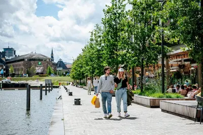 a man and woman walking down a sidewalk next to a river at Holiday Inn Hasselt by IHG in Hasselt