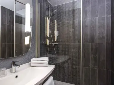 a bathroom with a sink and a shower with a mirror at ibis Liège Centre Opéra in Liège