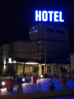 a hotel at night with a lit up sign at Globales Post Hotel & Wellness in Herstal