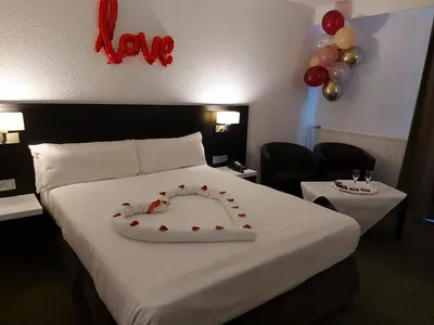 a bedroom with a bed with a love sign on it at Globales Post Hotel & Wellness in Herstal