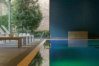 a swimming pool with a table and a swimming pool at Stiemerheide - The Urban Hotel & Golf Retreat 4 Star Superior in Genk
