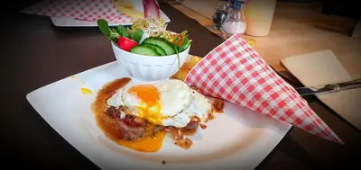 a plate with an egg and a salad on a table at Hotel Restaurant The Kings Head Inn in Voeren