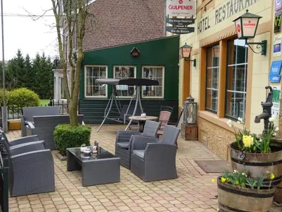 a patio with chairs and tables in front of a building at Hotel Restaurant The Kings Head Inn in Voeren
