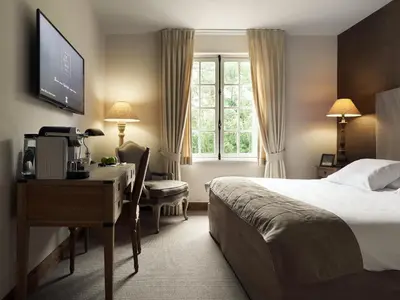 a hotel room with a bed and a desk and a computer at La Butte aux Bois a Small Luxury Hotel of the World in Lanaken