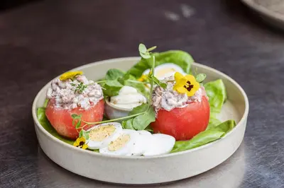 a bowl of salad with eggs and tomatoes and lettuce at Hotel The Century in Hasselt