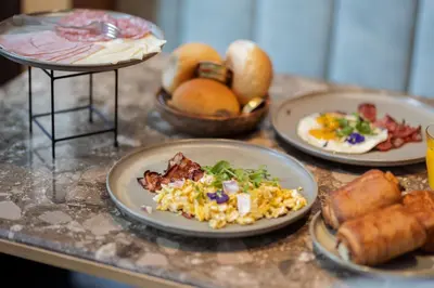 a table with plates of breakfast food and bread at Hotel The Century in Hasselt