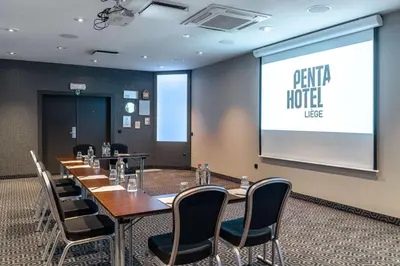 a meeting room with tables and chairs and a projection screen at pentahotel Liège in Liège