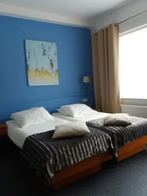 a bedroom with a blue wall and a bed with pillows at Hotel 'T Hert in Genk