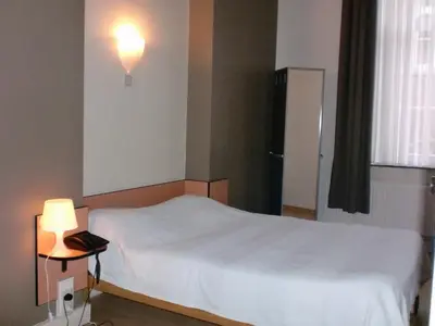 a bedroom with a white bed and a lamp at Hôtel Les Acteurs in Liège