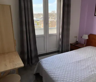 a bedroom with a bed and a large window at Hôtel Les Acteurs in Liège