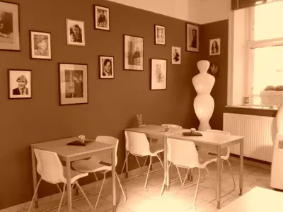 two tables and chairs in a room with pictures on the wall at Hôtel Les Acteurs in Liège