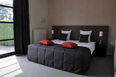 a bedroom with a large bed with two red pillows at Hotel Boomgaard in Lanaken