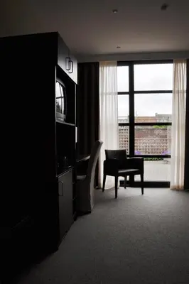 a living room with a table and a chair and a window at Hotel Boomgaard in Lanaken