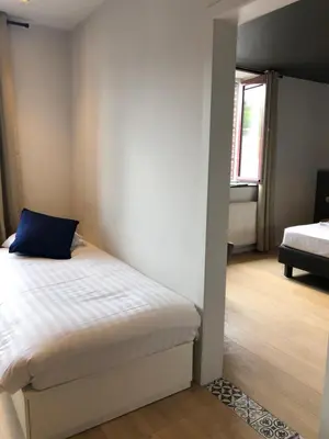 a bedroom with a bed with a blue pillow on it at Hotel Le Cygne d'Argent in Liège