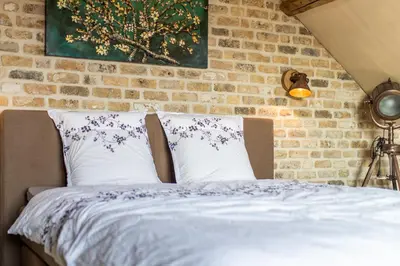 a bed with two pillows in front of a brick wall at Relax B&B Lavendine Pure in Genk