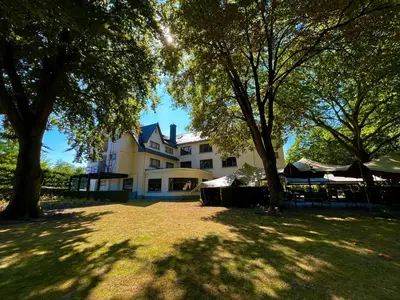 a large white house with trees in front of it at Hotel Mardaga in As