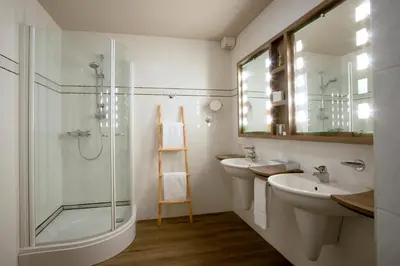 a bathroom with two sinks and a glass shower at Hotel Mardaga in As
