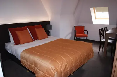 a bedroom with a bed and a table and chairs at Hotel Malpertuus in Riemst