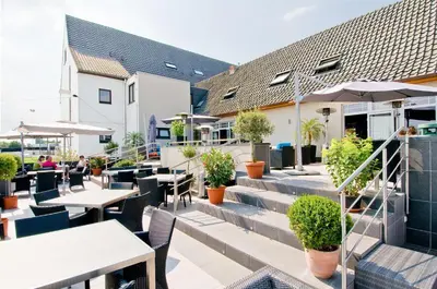 an outdoor patio with tables and chairs and plants at Hotel Malpertuus in Riemst