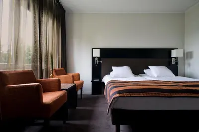 a hotel room with a bed and two chairs at Eurotel Lanaken in Lanaken