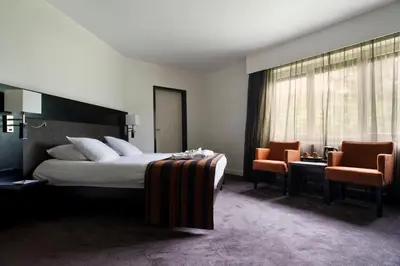 a hotel room with a bed and two chairs at Eurotel Lanaken in Lanaken