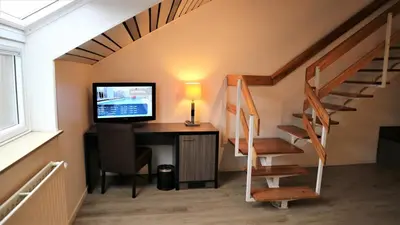 a room with a desk with a computer and a staircase at Eurotel Lanaken in Lanaken