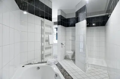a white bathroom with a tub and a toilet at Eurotel Lanaken in Lanaken