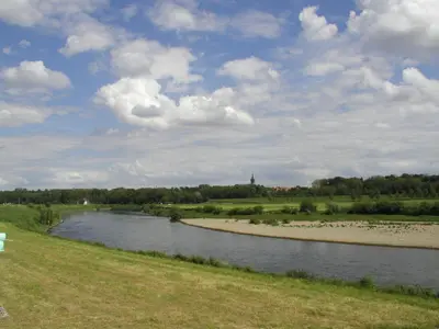 a river in a field with a cloudy sky at Eurotel Lanaken in Lanaken