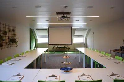 a conference room with tables and chairs and a projection screen at Eurotel Lanaken in Lanaken