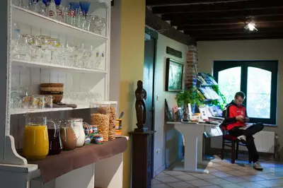 a woman sitting in a chair in a room with a counter at B&B De Dubbelmolen in Tongeren