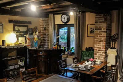 a dining room with a table and a clock on the wall at B&B De Dubbelmolen in Tongeren