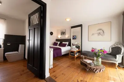 a bedroom with a bed and a couch and a table at B&B Montenakerhof in Riemst